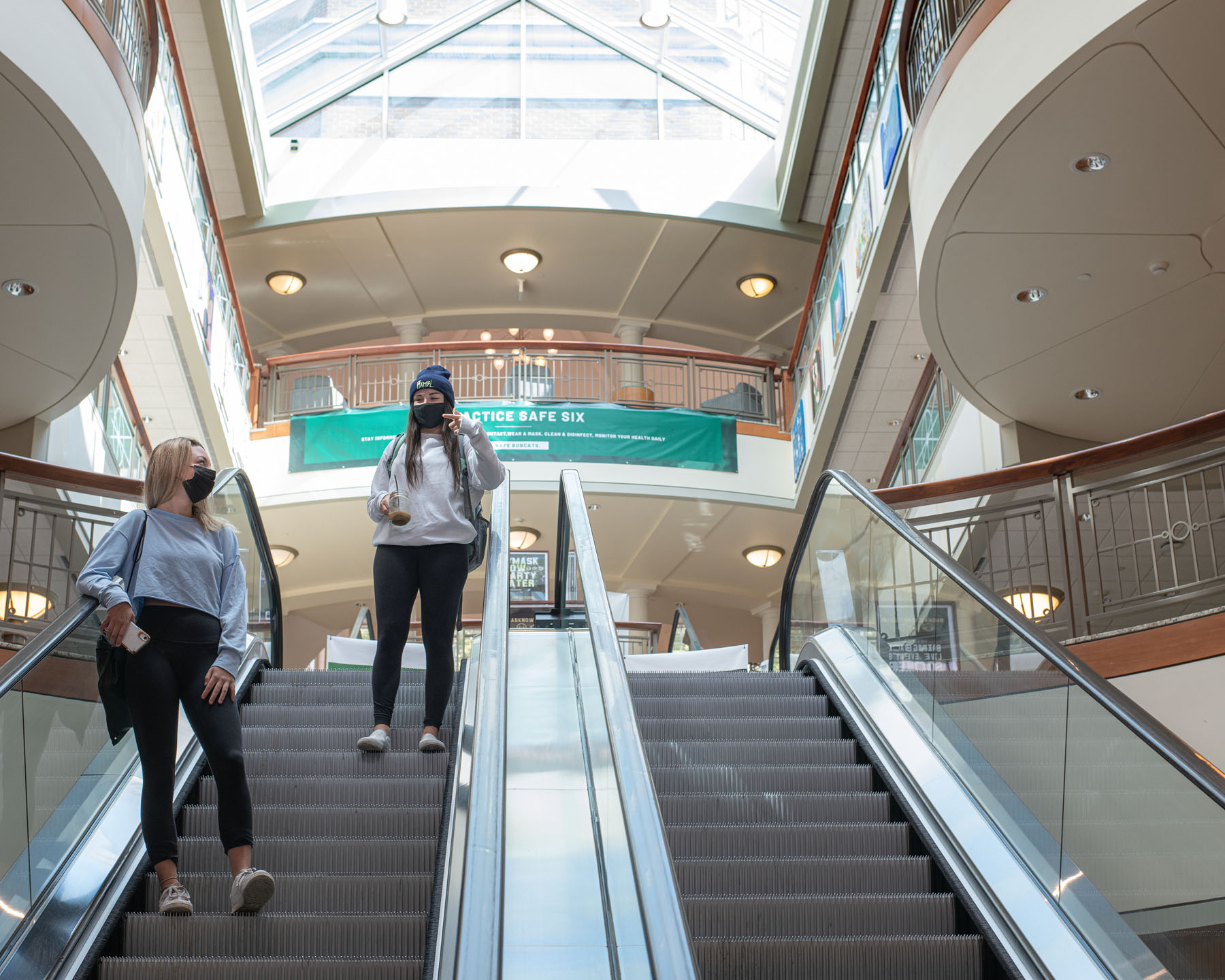 Two students descend Baker University Center on the escalator