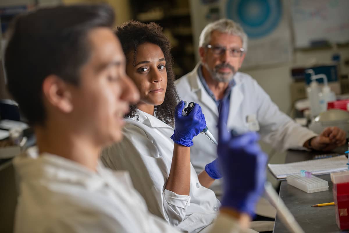 Biology students working in a lab with a professor