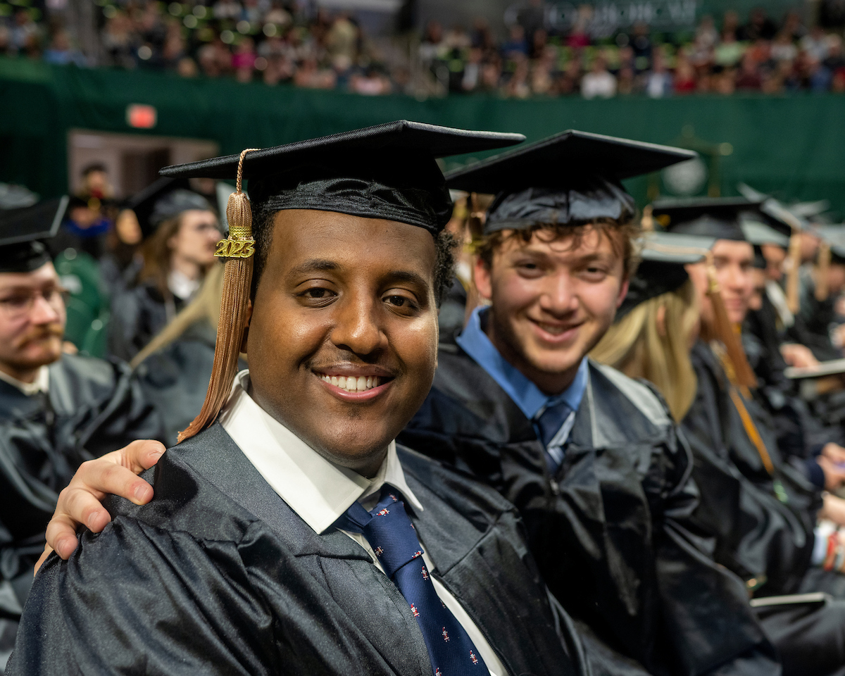 Male graduates smile into camera at fall commencement 