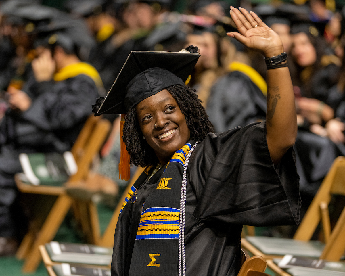 Female student waves to the camera during Fall Commencement 2023