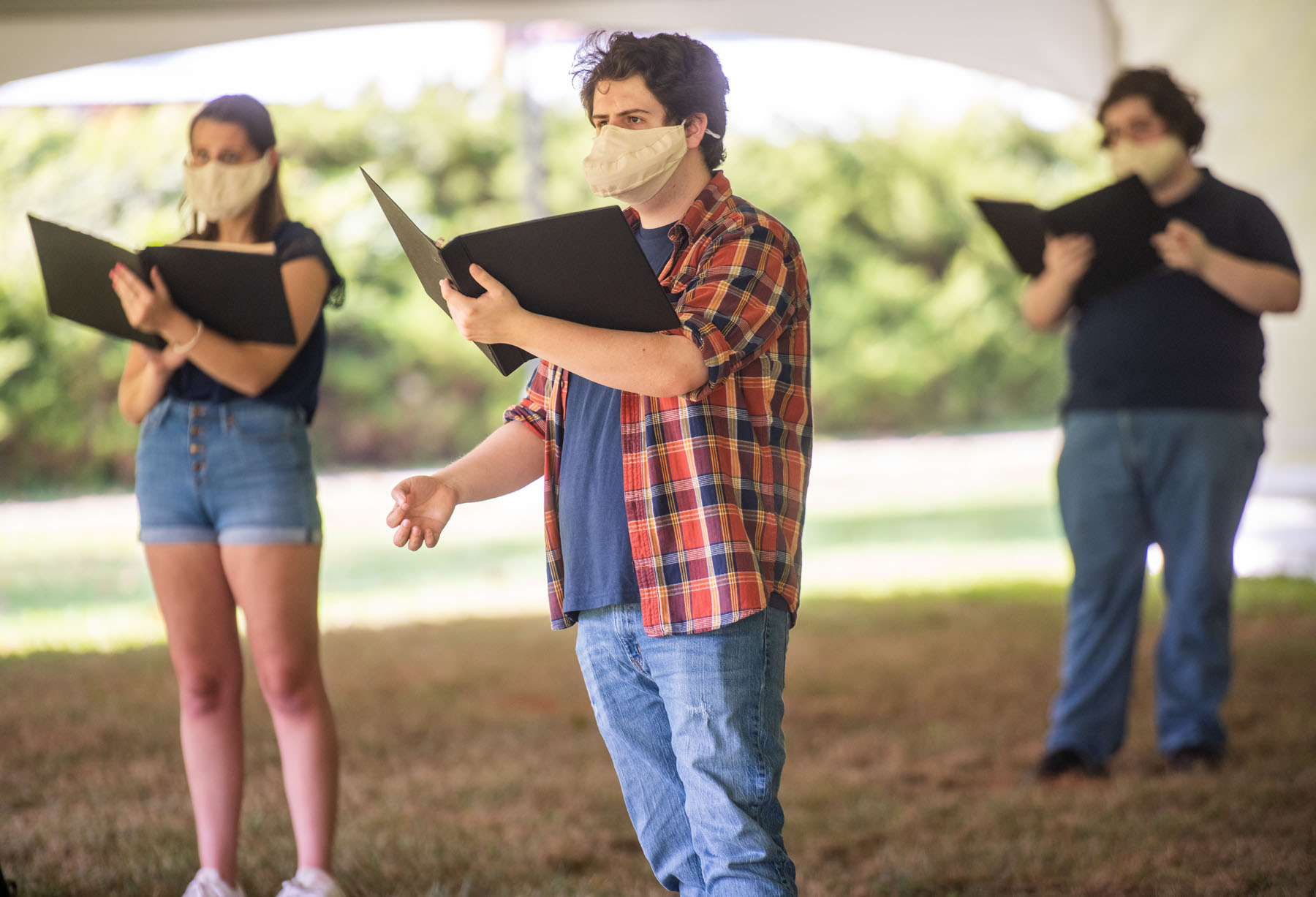 Students practice singing outside in a large tent for fear of indoor contact