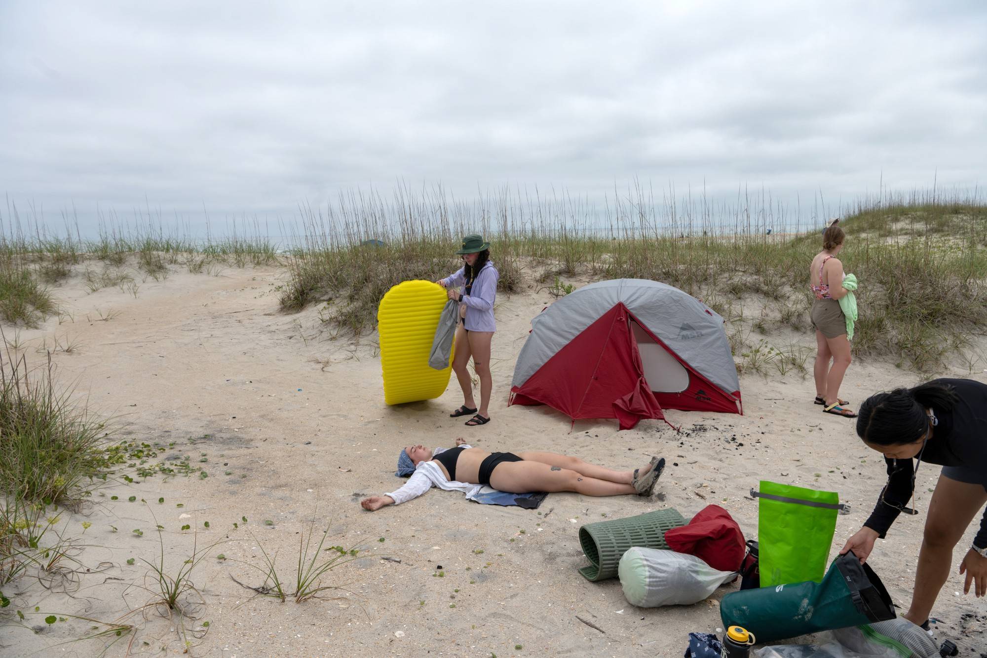 Students camped in the shadow of Cape Lookout Lighthouse on the third night in the Outer Banks. Autumn Warren rests for a moment after pitching her tent on the beach.