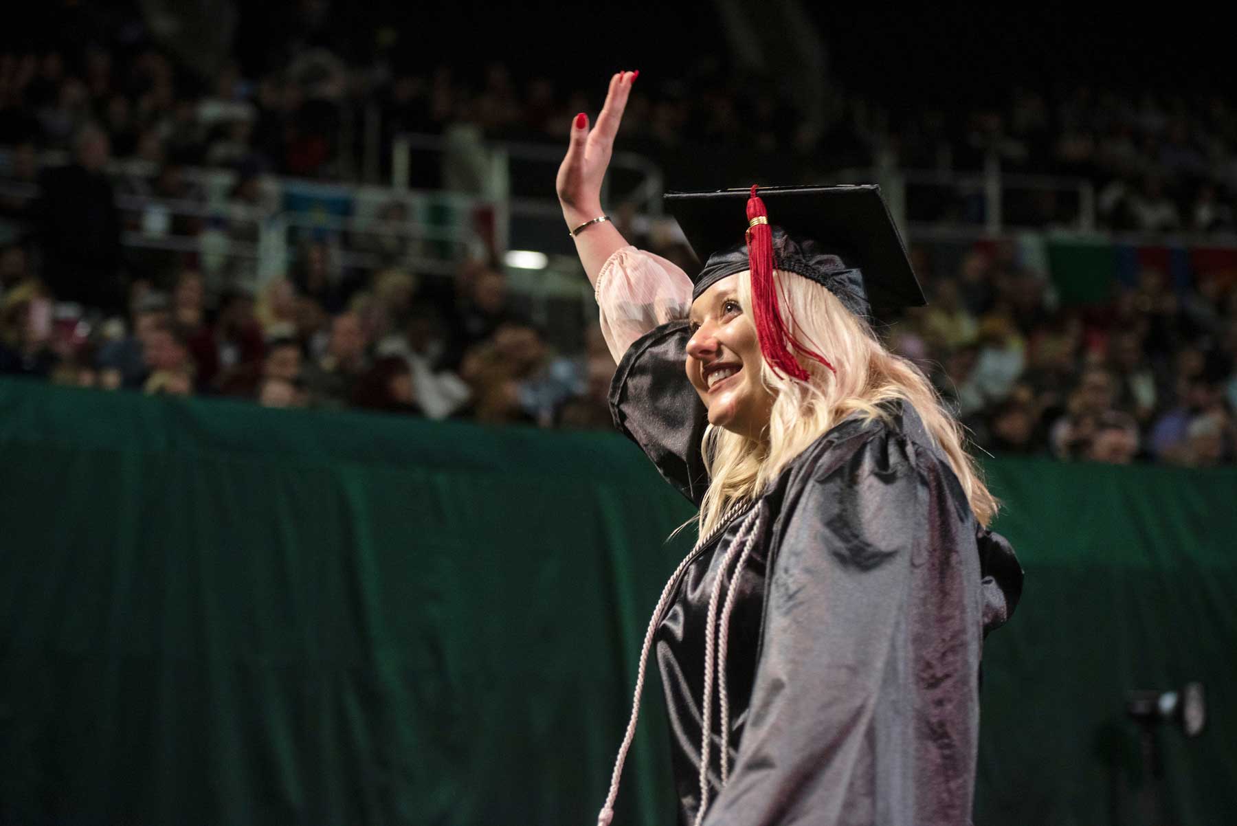 Carly McFadden waving to the crowd during graduation.