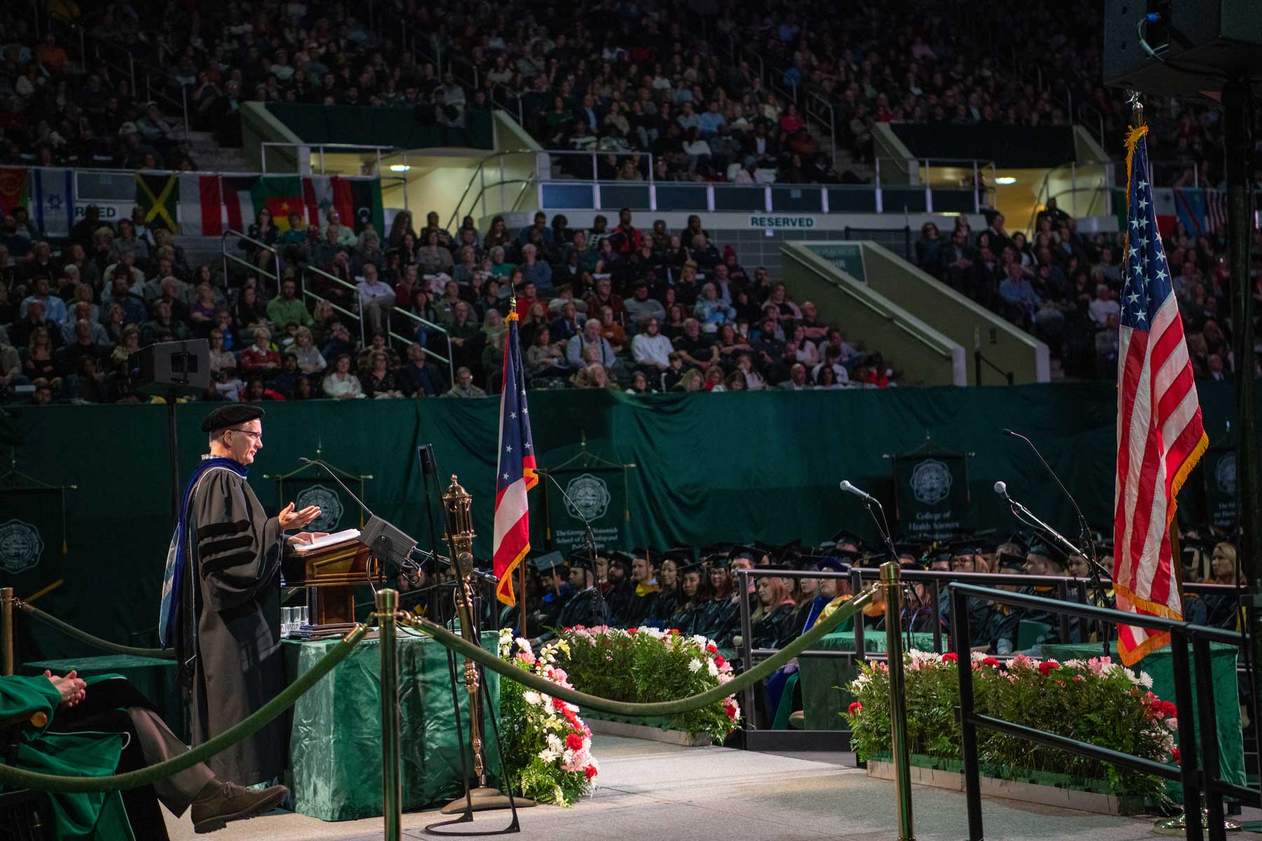 A side portrait of Steve Evans delivering a speech on stage during 2019 Fall Commencement.