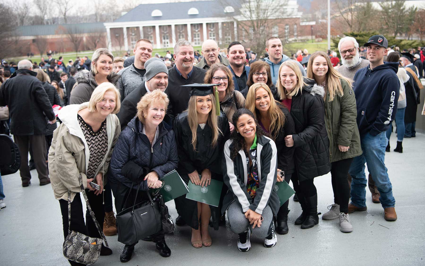 Graduate poses with her family and friends after Fall Commencement.