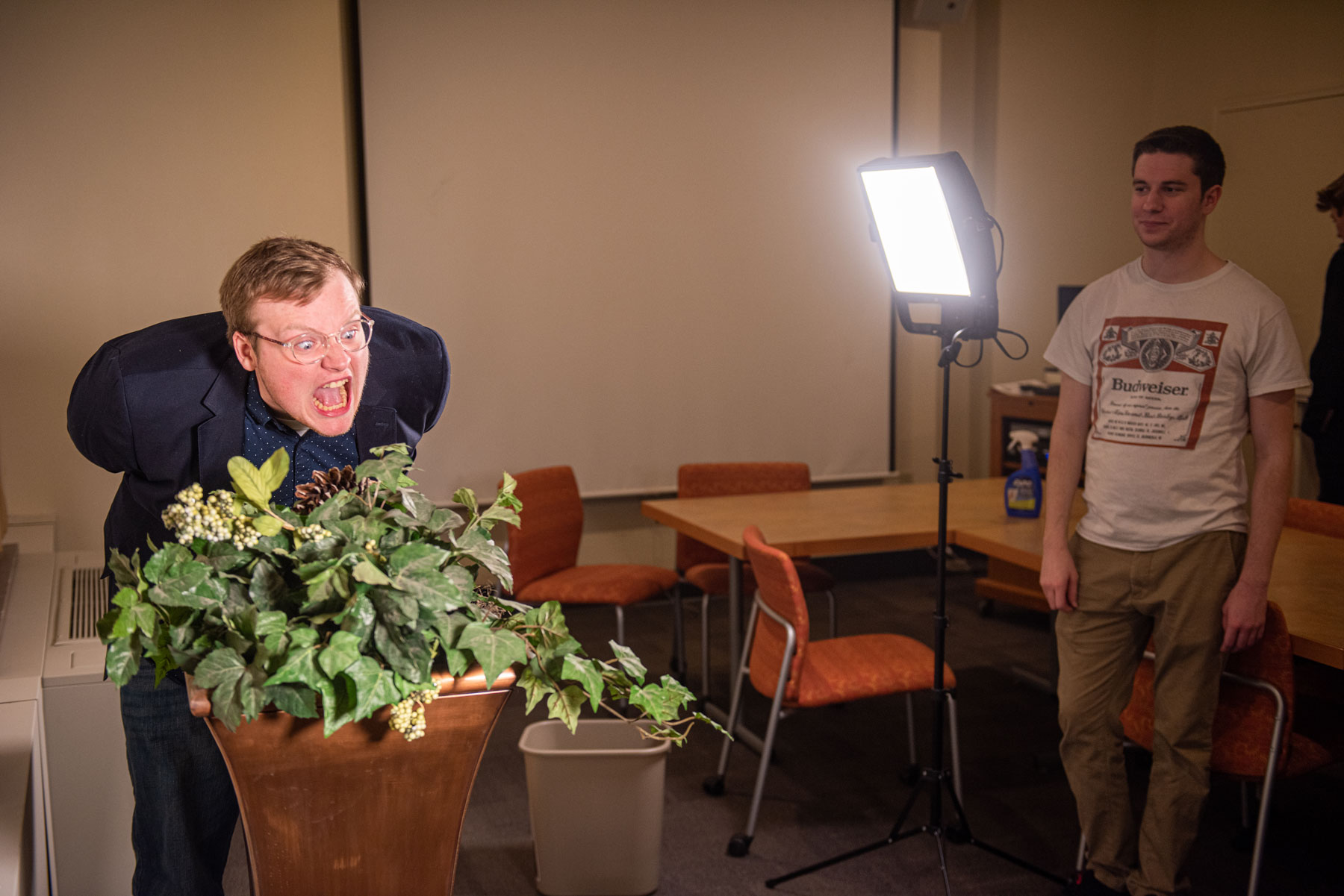A man illuminated by video lighting shouting at a plant