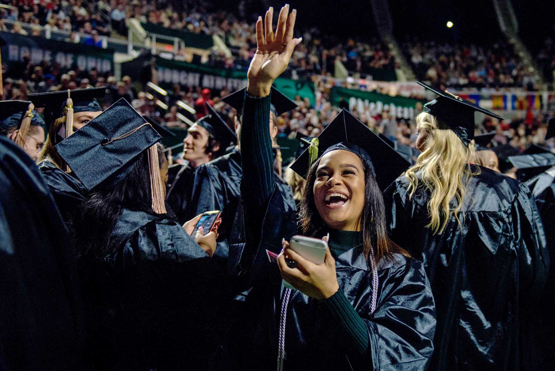Excited students celebrating in cap and gown at 2019 Fall Commencement
