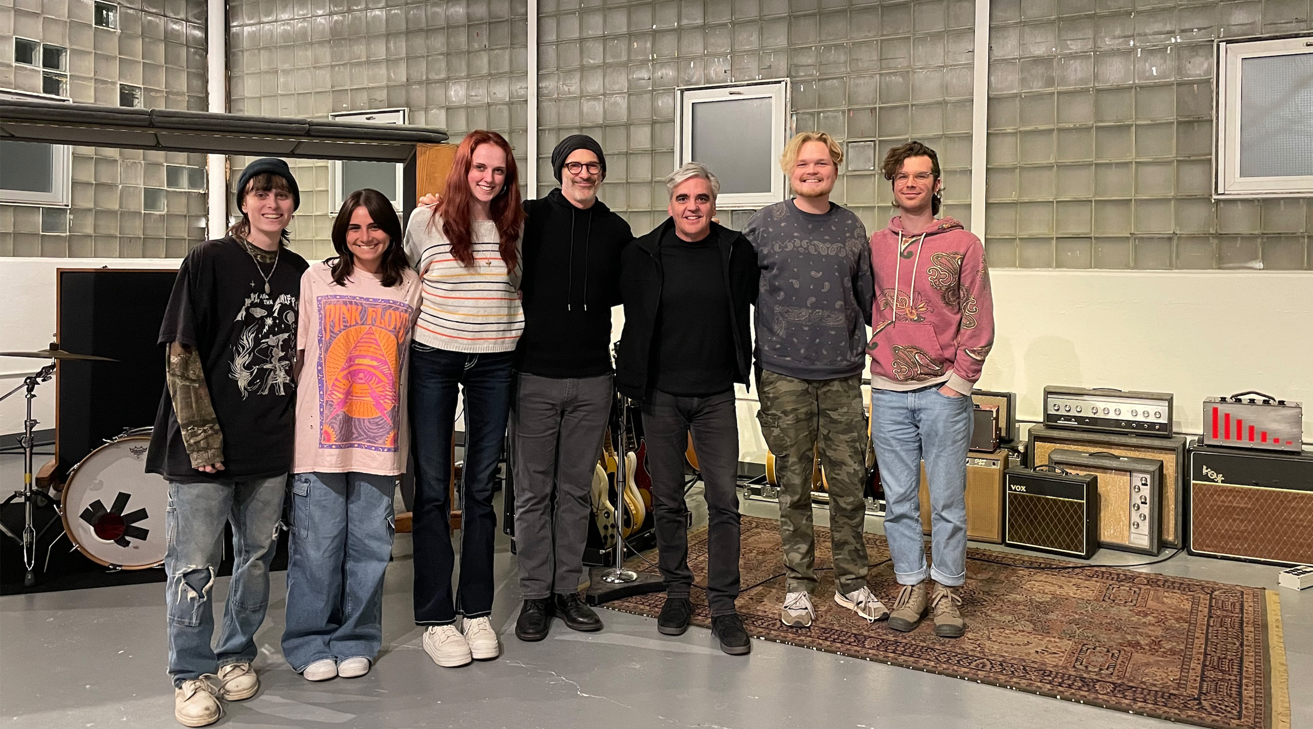 A group of students pose for a photo in a large music studio