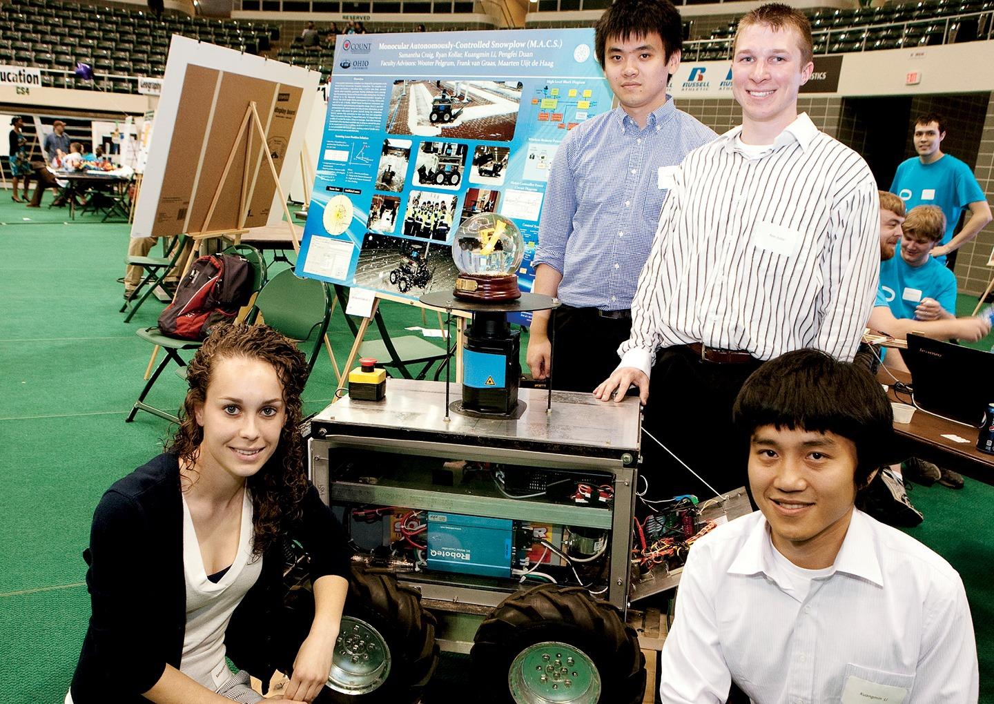 Pengfei “Phil” Duan, MS ’11, PHD ’18, [SECOND FROM LEFT] and a team of fellow engineering students show off their robotic snowplow at the 2012 Student Expo. Photo by Wayne Thomas, MA ’12