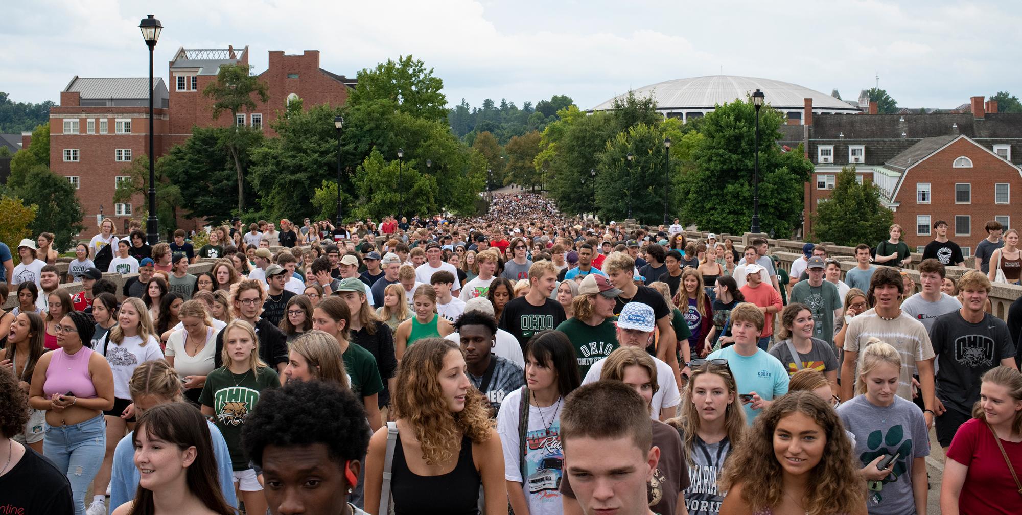 Many Ohio University First-year students walk across a bridge.