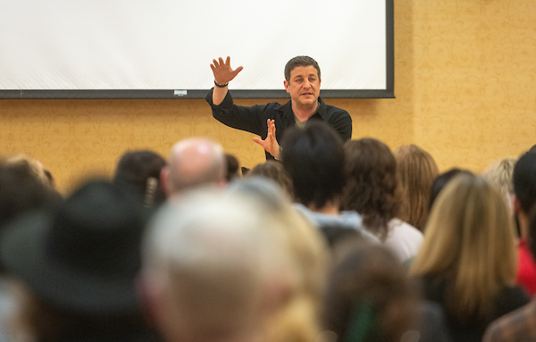 A presenter gestures in front of an audience