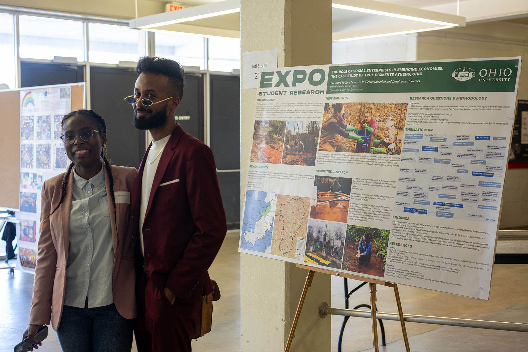 two students stand in front of their research project presentation