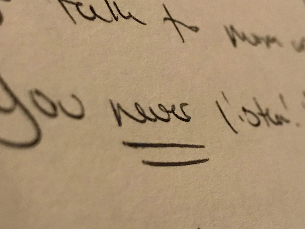 The words you never listen! Are written and are in the middle of the photograph, stretching out to both sides. Never is underlined twice. The words “talk to mom” are barely visible as they are written off the photograph and blurred.