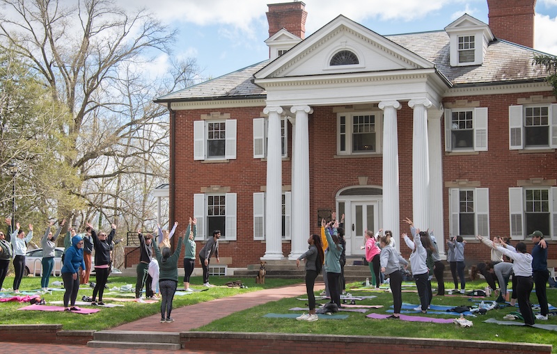 A group practices yoga on the lawn of a University building