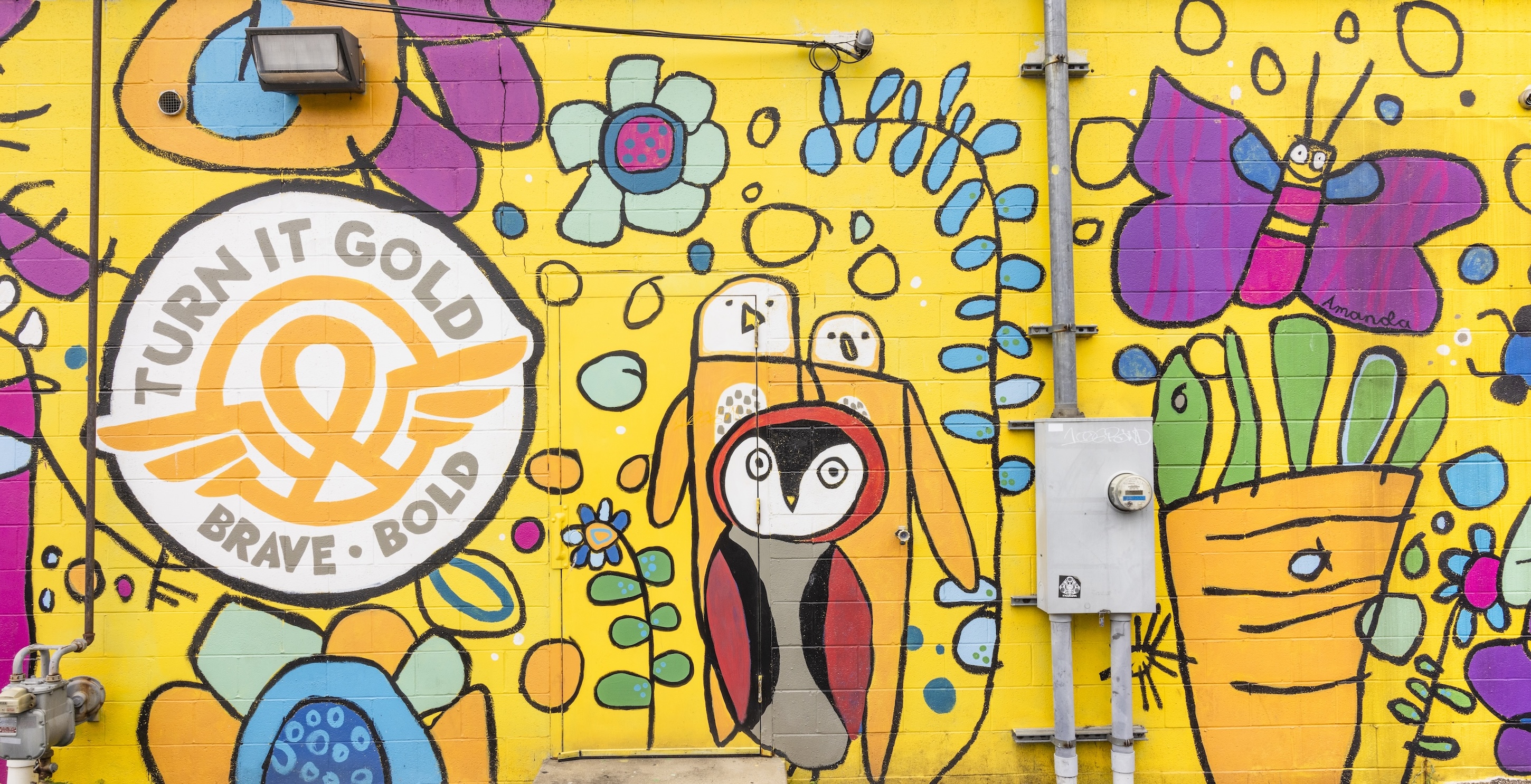 A colorful mural featuring animals and butterflies, with the words "Turn it Gold: Brave/Bold"