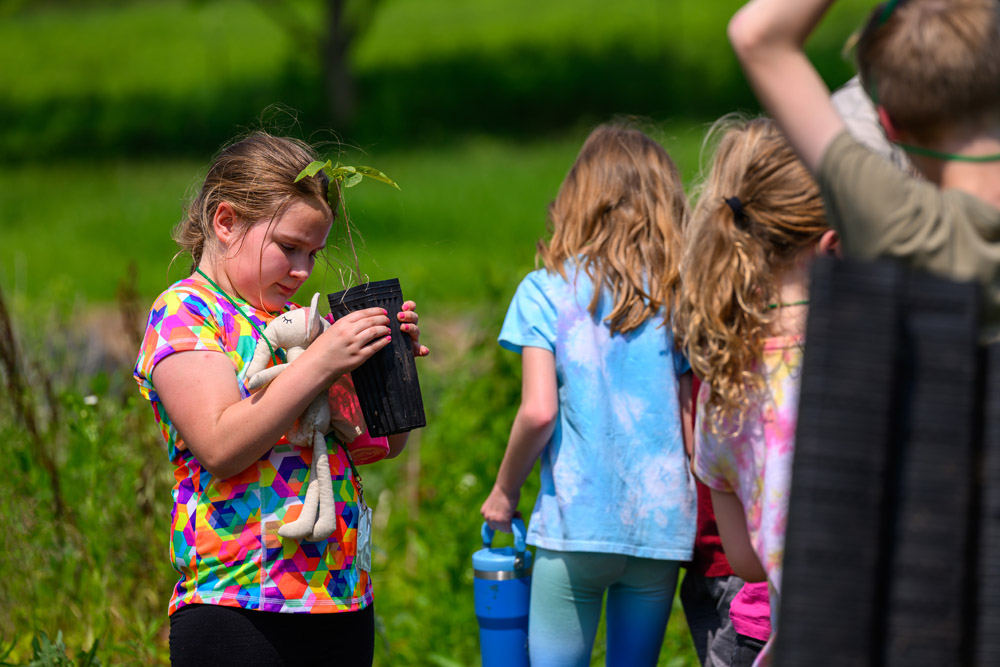 A camper holding up a plant and looking into it