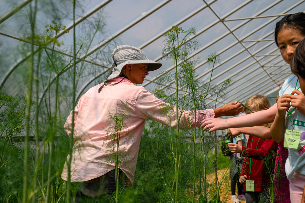 A counselor showing campers different planets in a greenhouse.