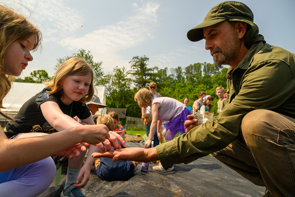 A counselor holding up an object for campers to look at. 