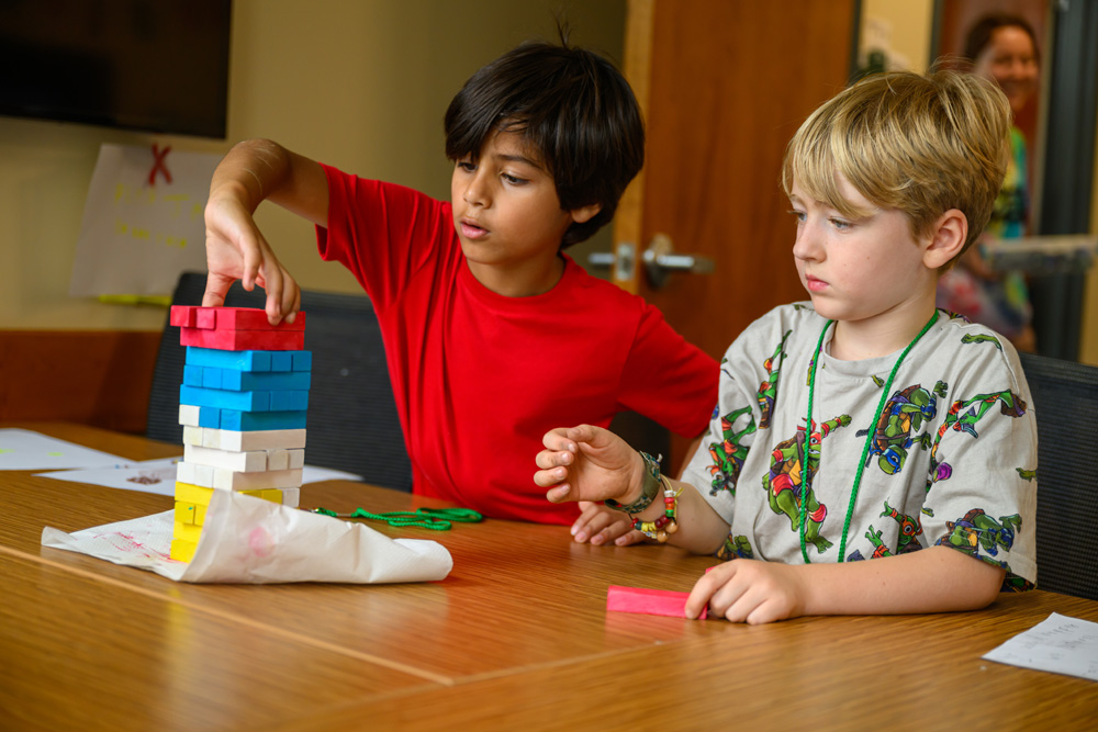 Two campers building with blocks in a classroom.