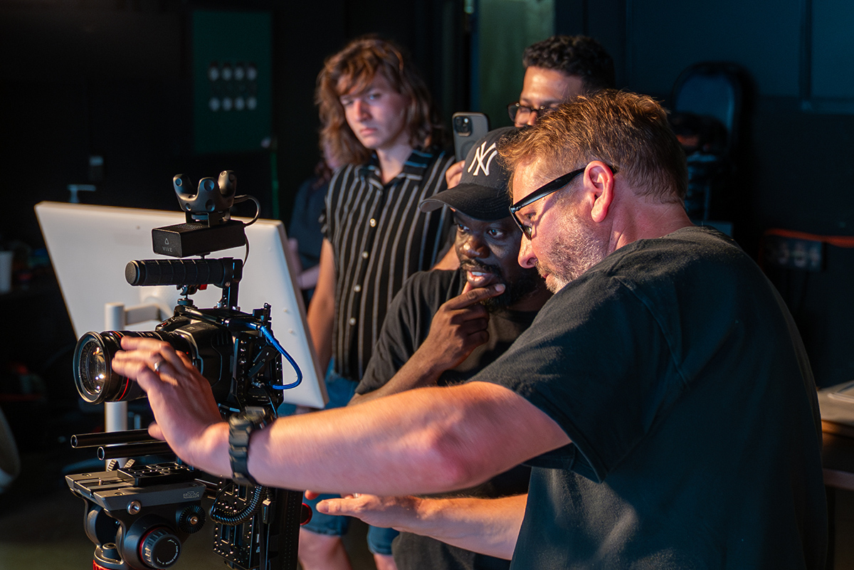 Instructor and students look at a camera attached to the Scripps College of Communication's new LED video wall