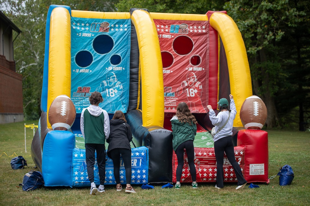 Fans throw footballs into an inflatable game at a tailgate area