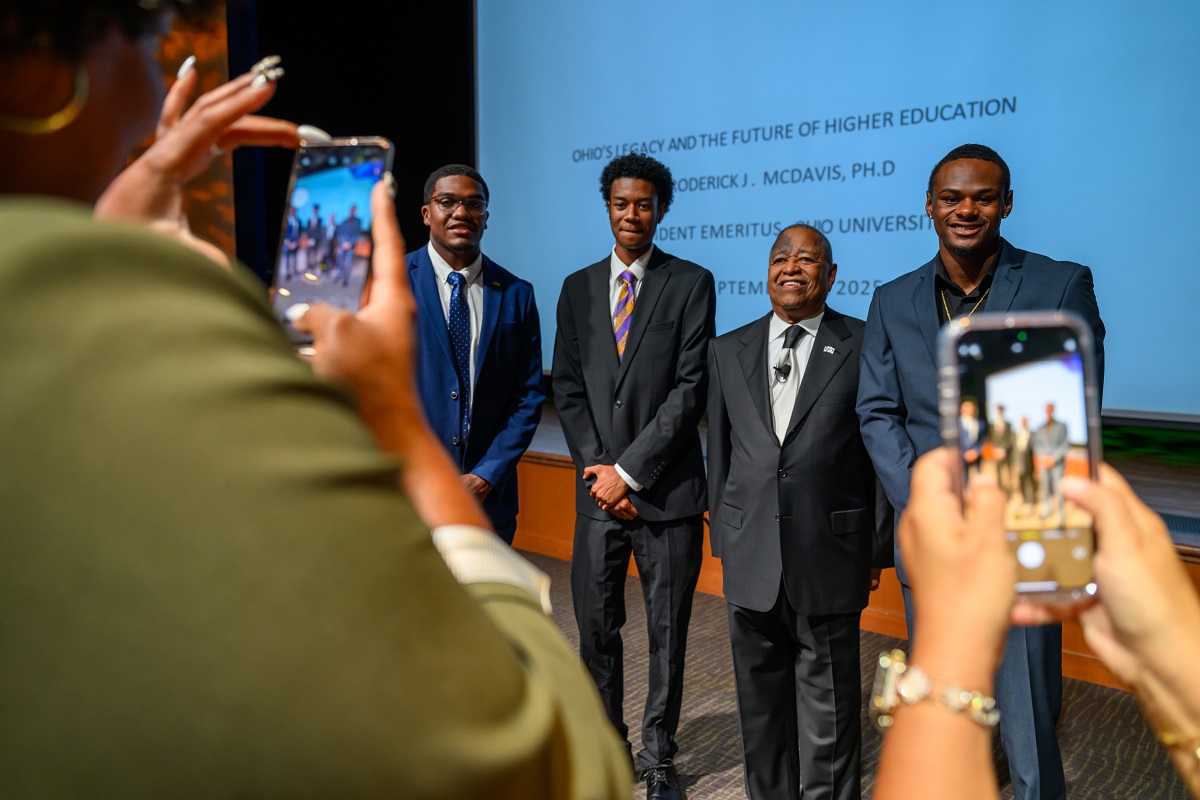 President McDavis stands with three OHIO students for a photo after the lecture in the Baker Theater