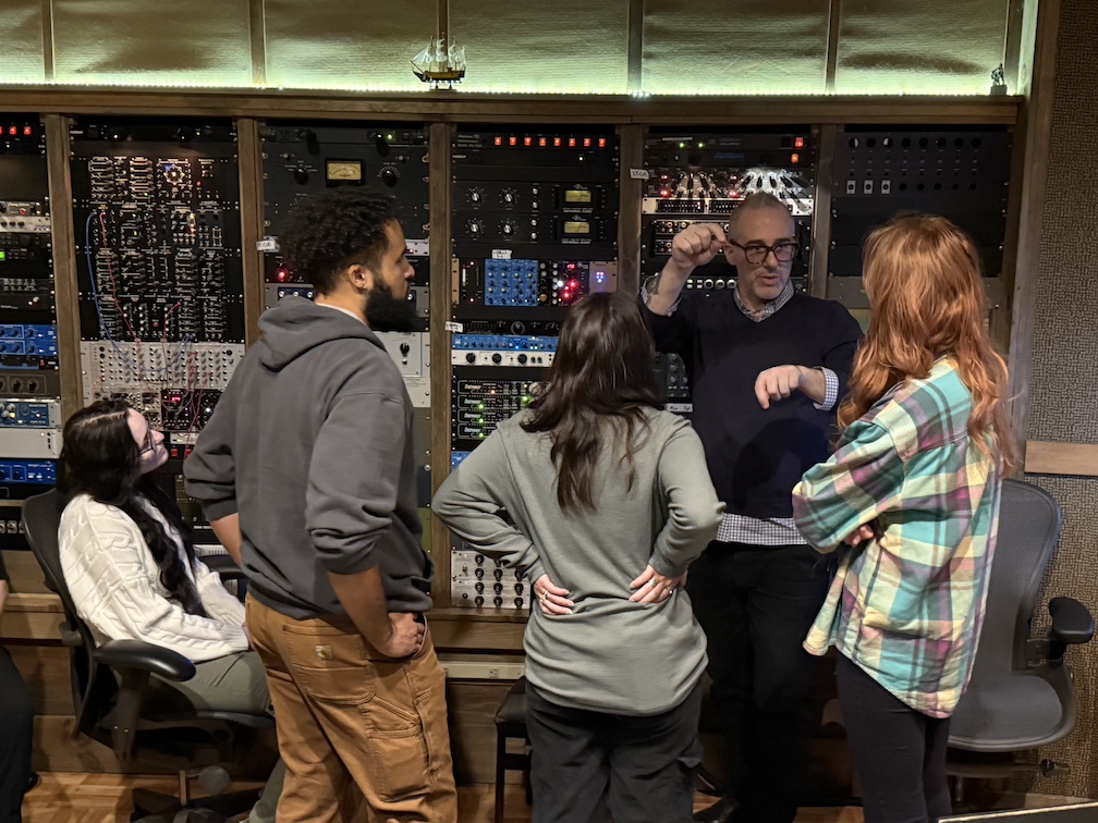 Students listening to professional working in recording studio