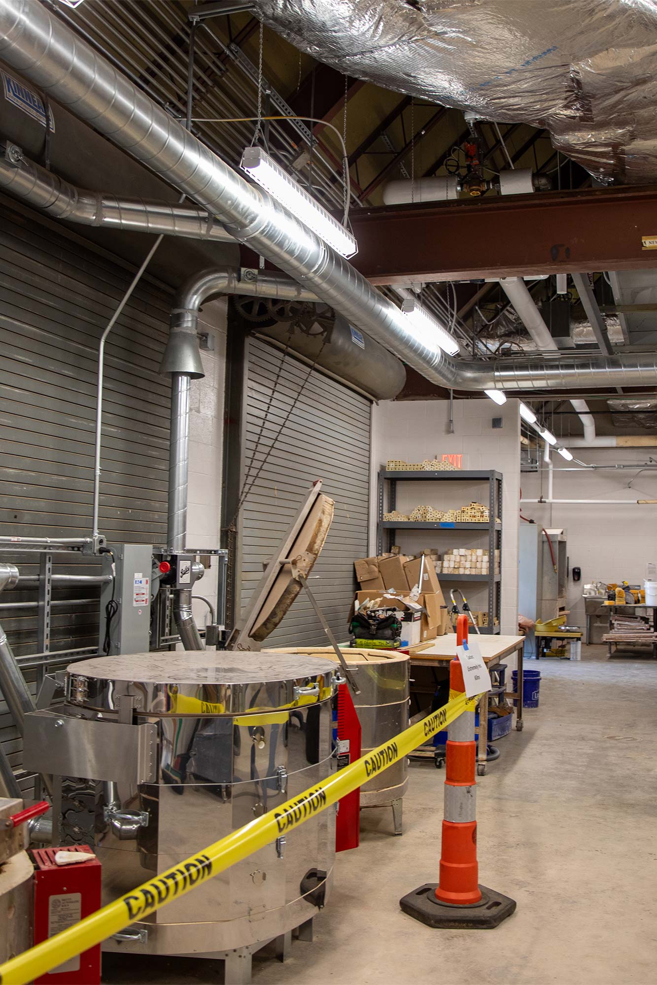 several electric kilns, blocked by caution tape warning guests of their high temperatures, in a large studio workspace
