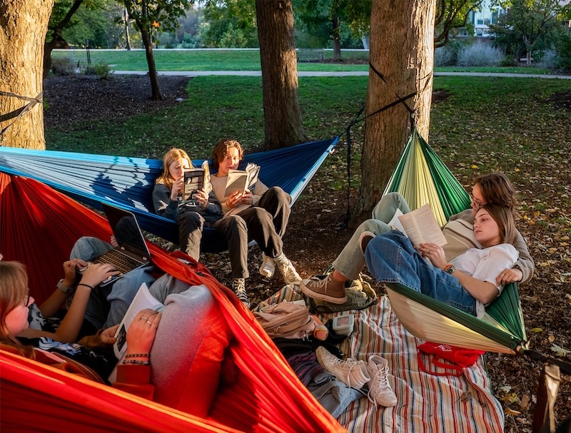 A group of students lounge in hammocks, reading books