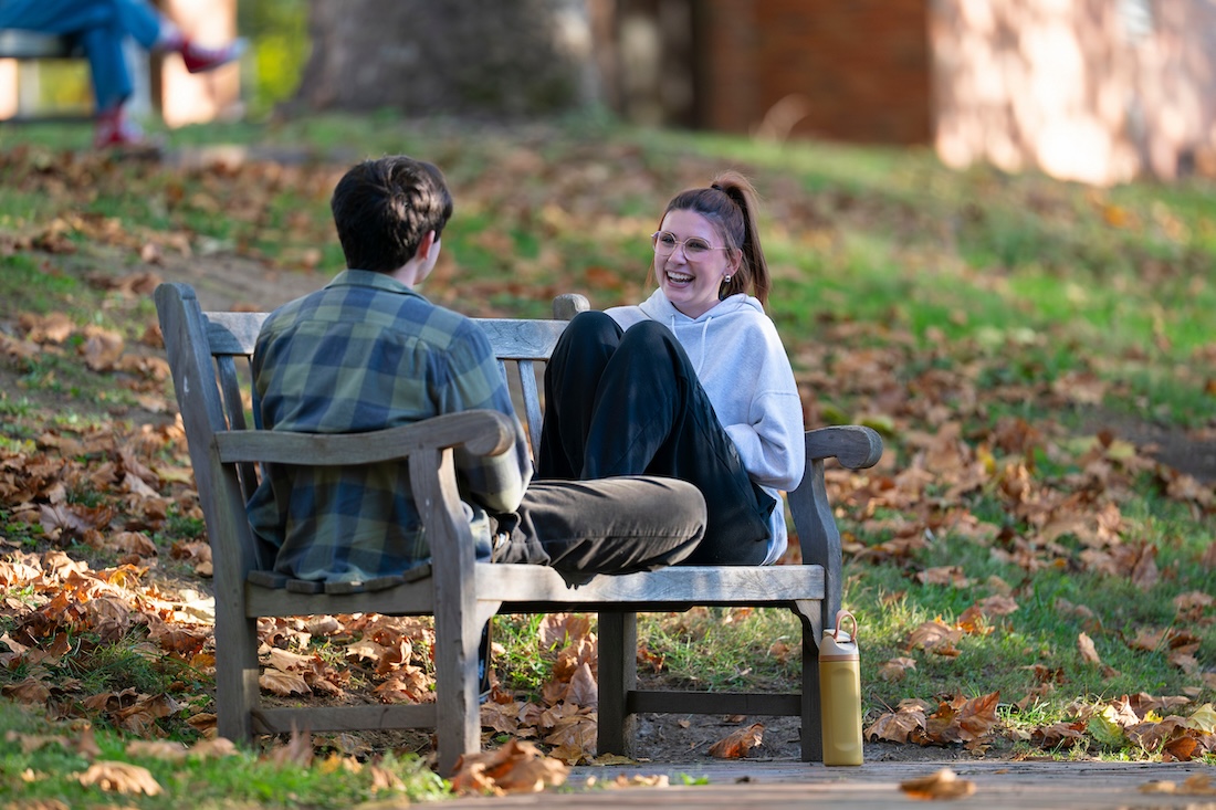 Two students laugh on a park bench