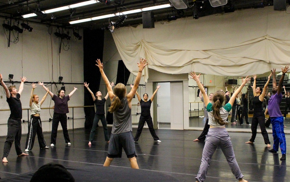 Students in circle stretching at dance studio