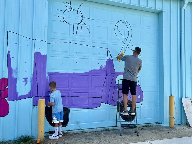 Women’s Basketball coach Bob Bolden paints the mural with his son