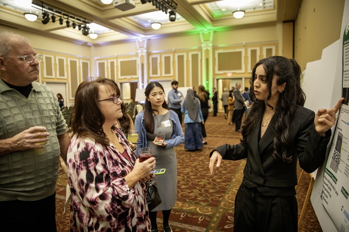 An OHIO student discusses her research project with audience members in the event in the Baker University Center Ballrom