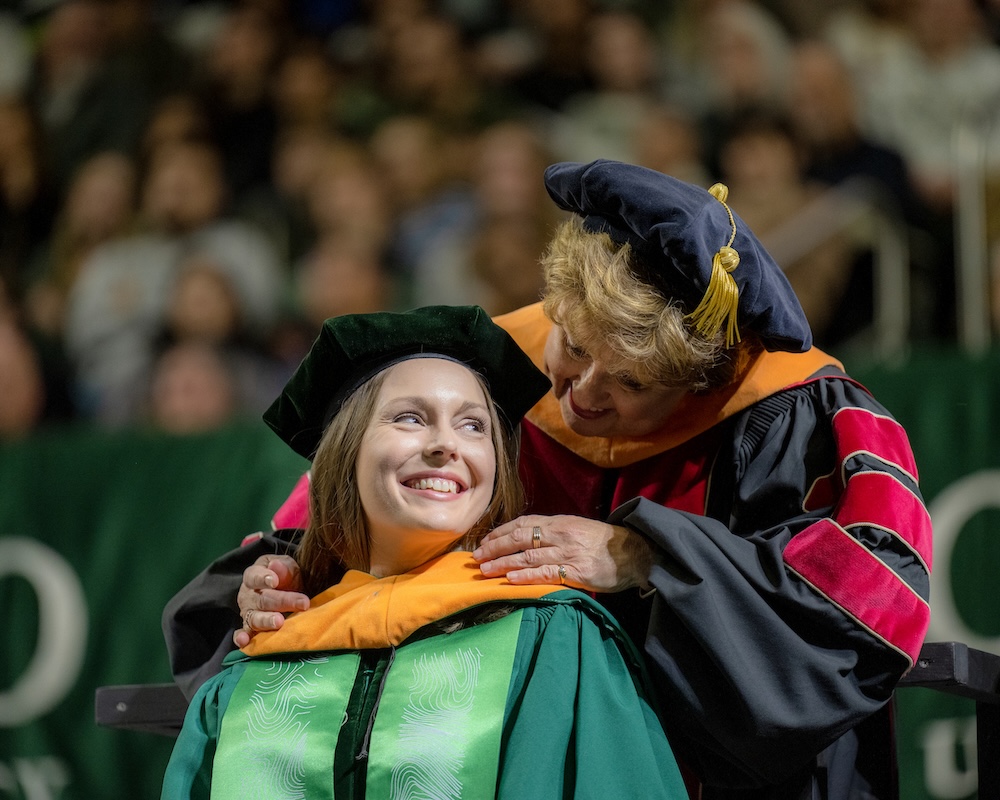 A faculty member places a doctoral hood for an OHIO graduate