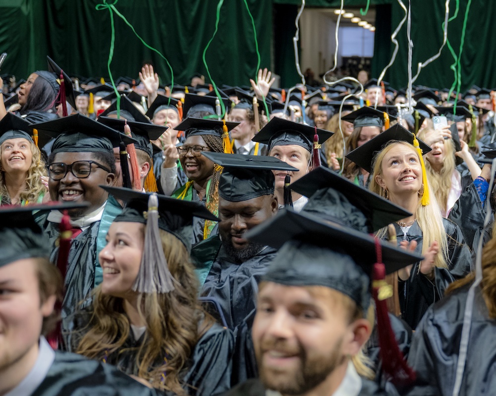 a crowd of graduates watch streamers fall from the ceiling