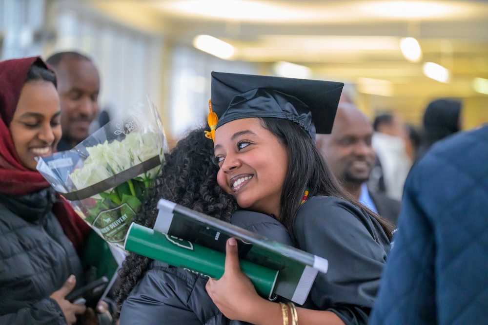 a new graduate embraces someone in the lobby of the Convo