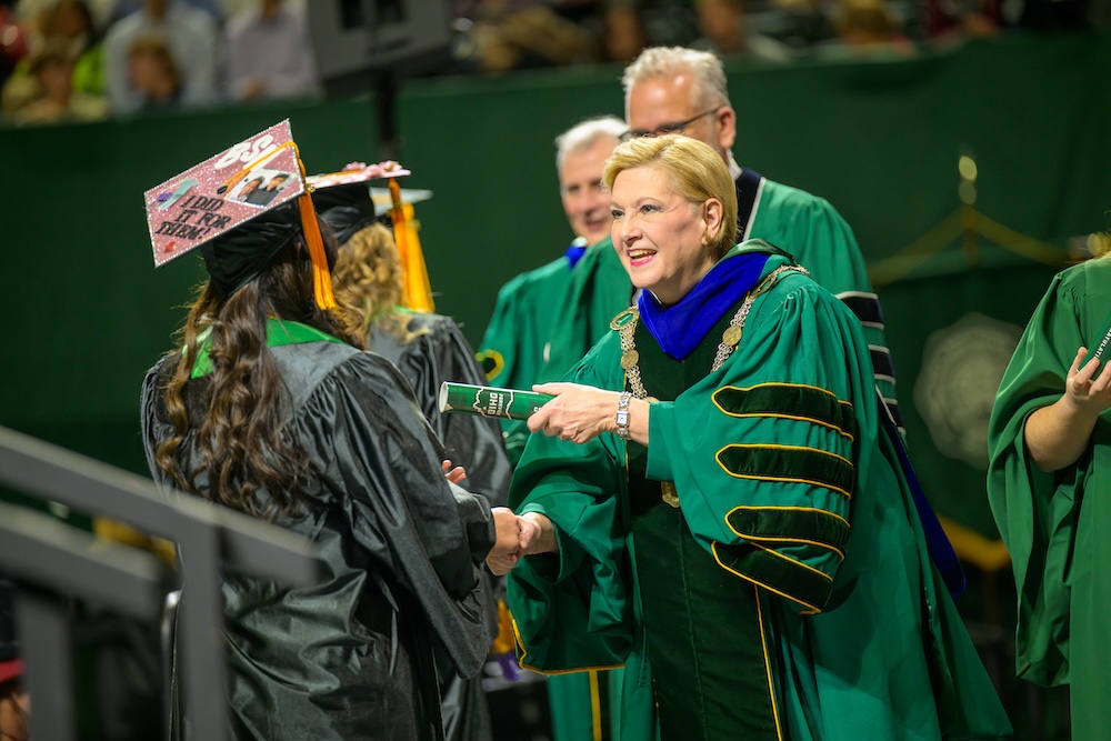 President Lori Stewart Gonzalez shakes hands with a new graduate