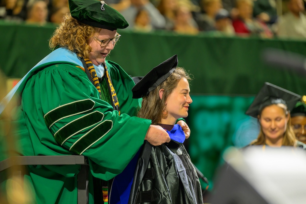 A faculty member places a doctoral hood for an OHIO graduate