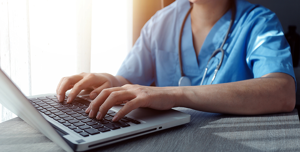 A nurse works at a computer