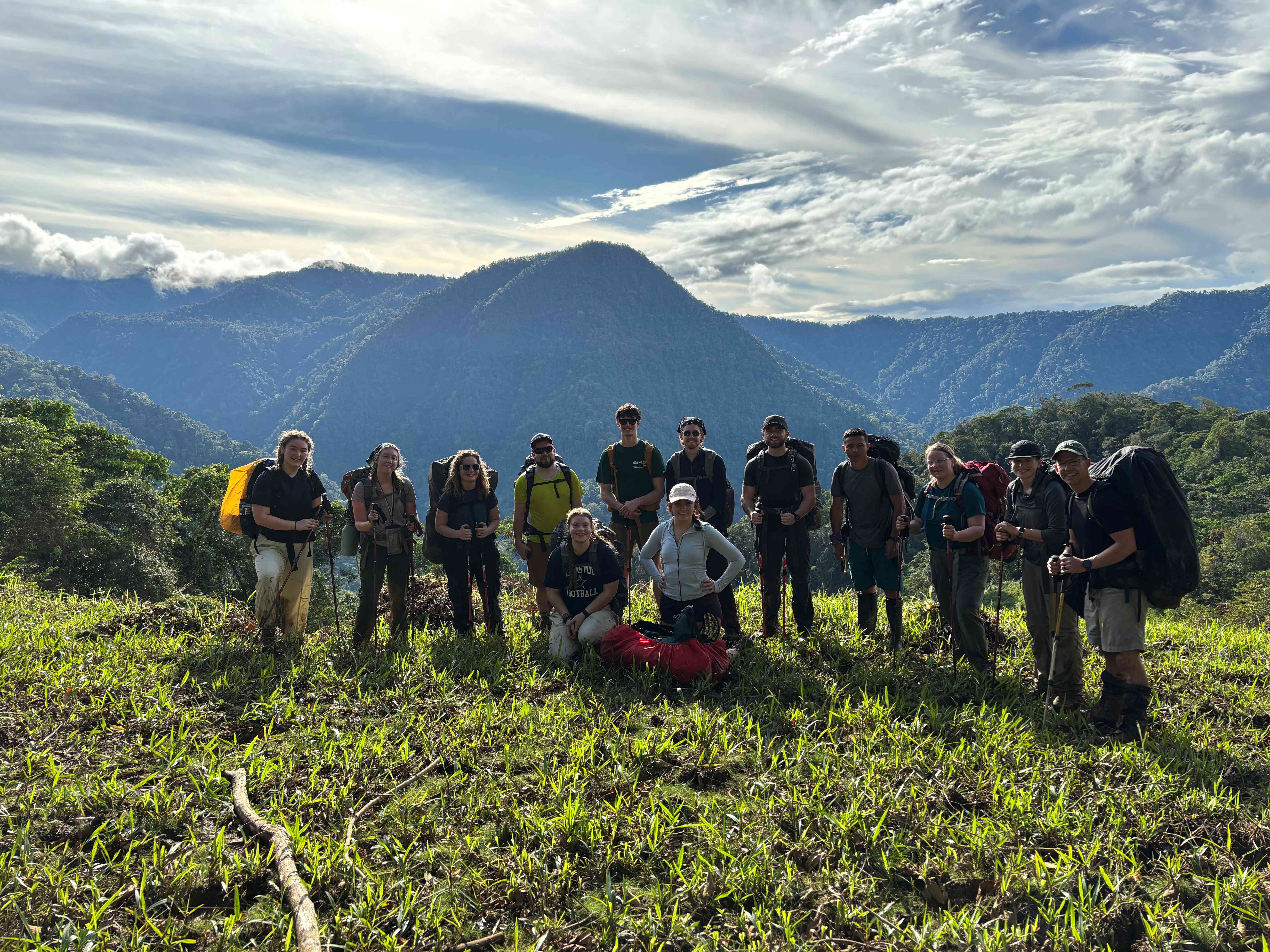 A group of hikers standing atop a forested hillscape.