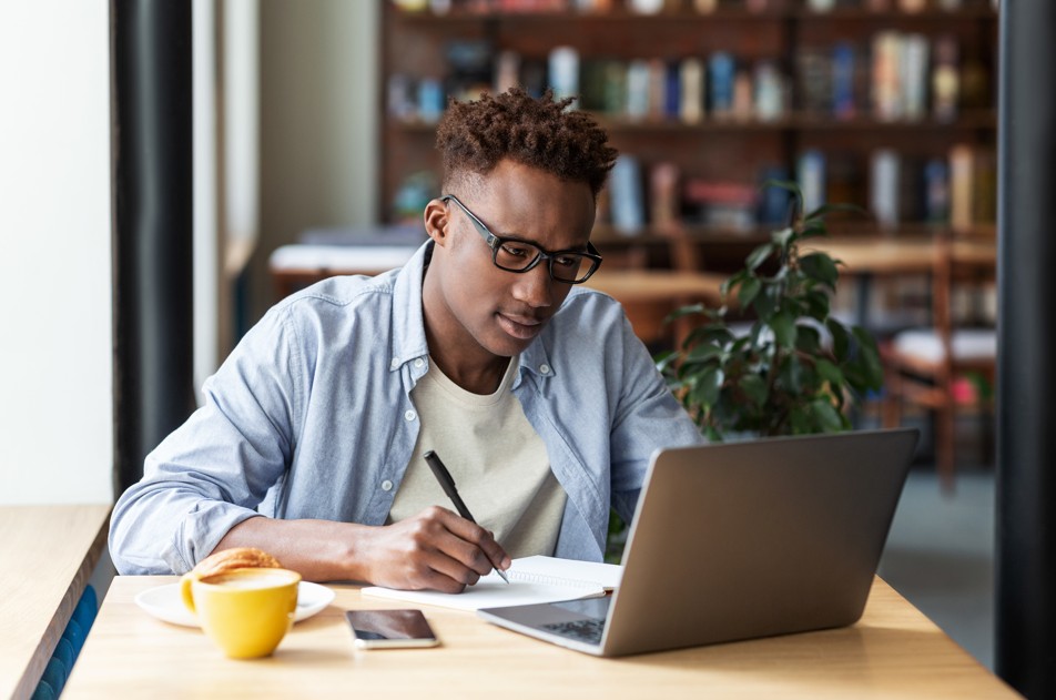A man sitting at a desk using his laptop to study.