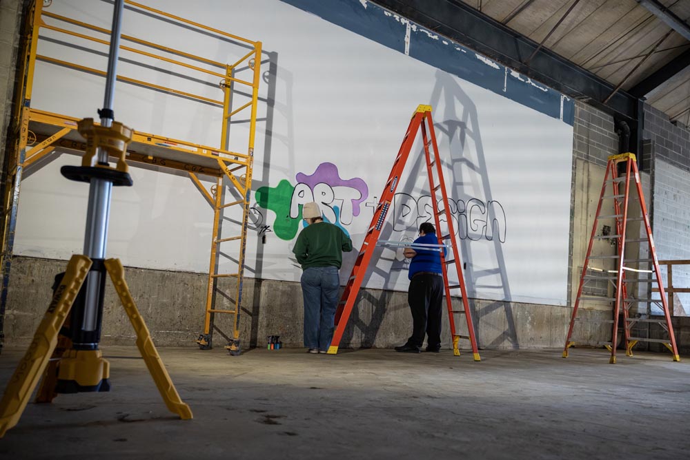 Artists painting on the wall in Seigfred hall.