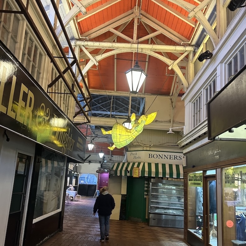 A sculpture of Alice from Alice in Wonderland hanging from the ceiling of a market in the UK