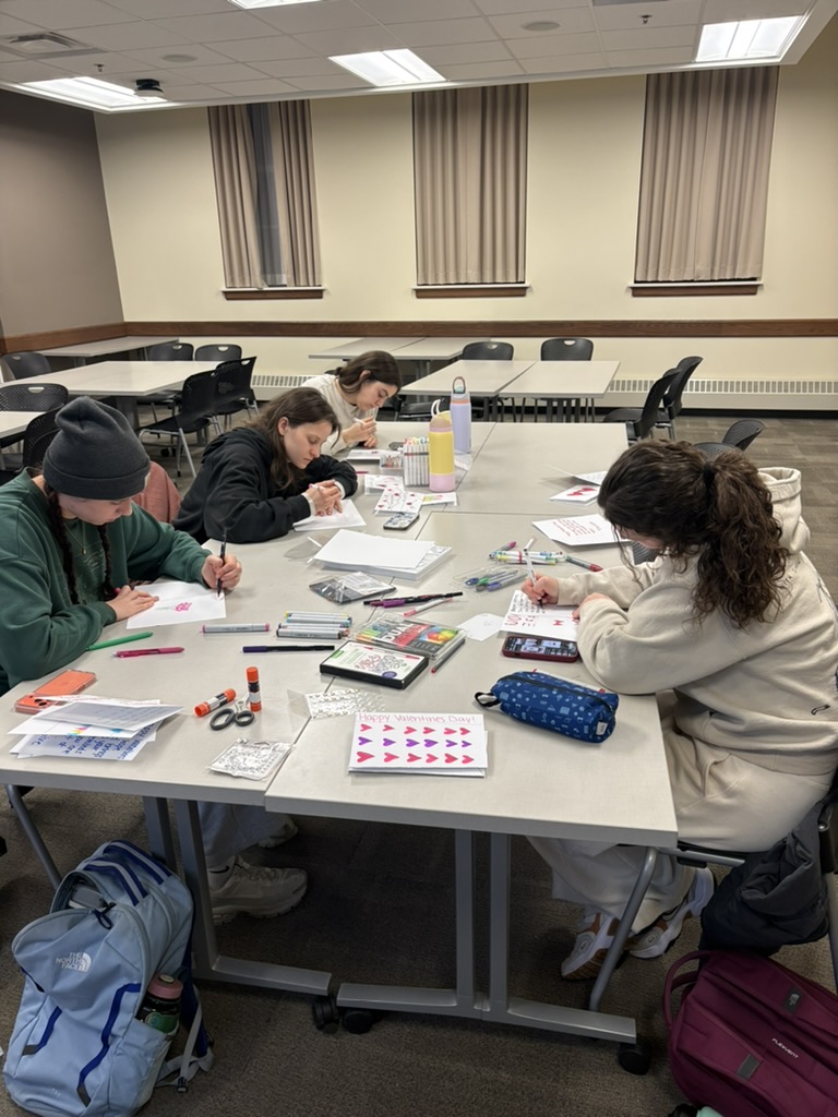 People sitting down at a table doing arts and crafts.