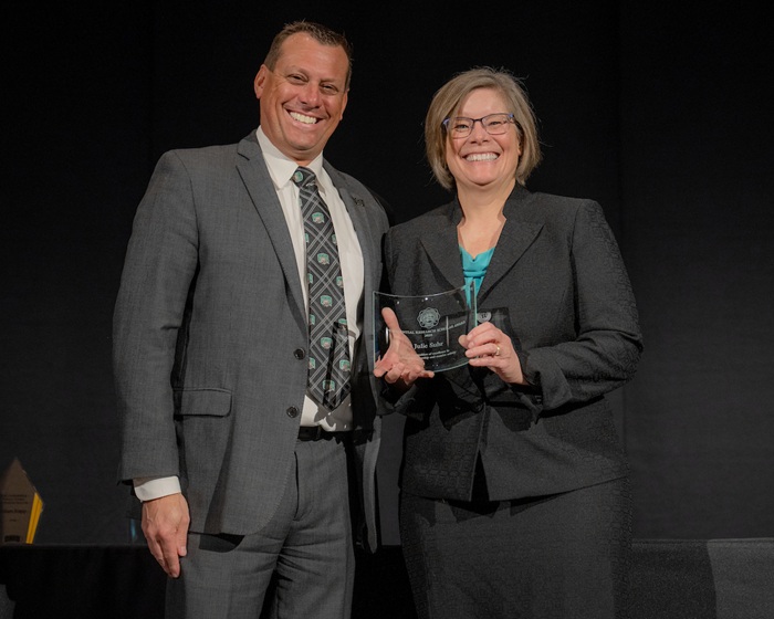 Eric Muth stands with Julie Suhr, who is holding the award