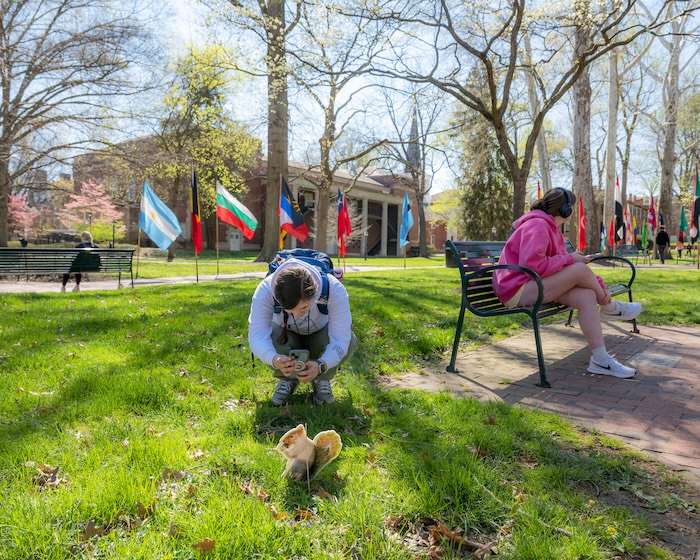 An OHIO student scans in the QR code on a squirrel image as part of the scavenger hunt on the College Green.