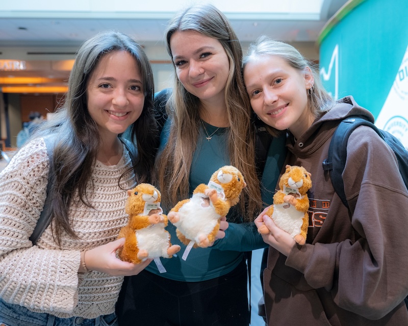 Three OHIO students hold stuffed animal squirrels at an OHIO Giving Day event
