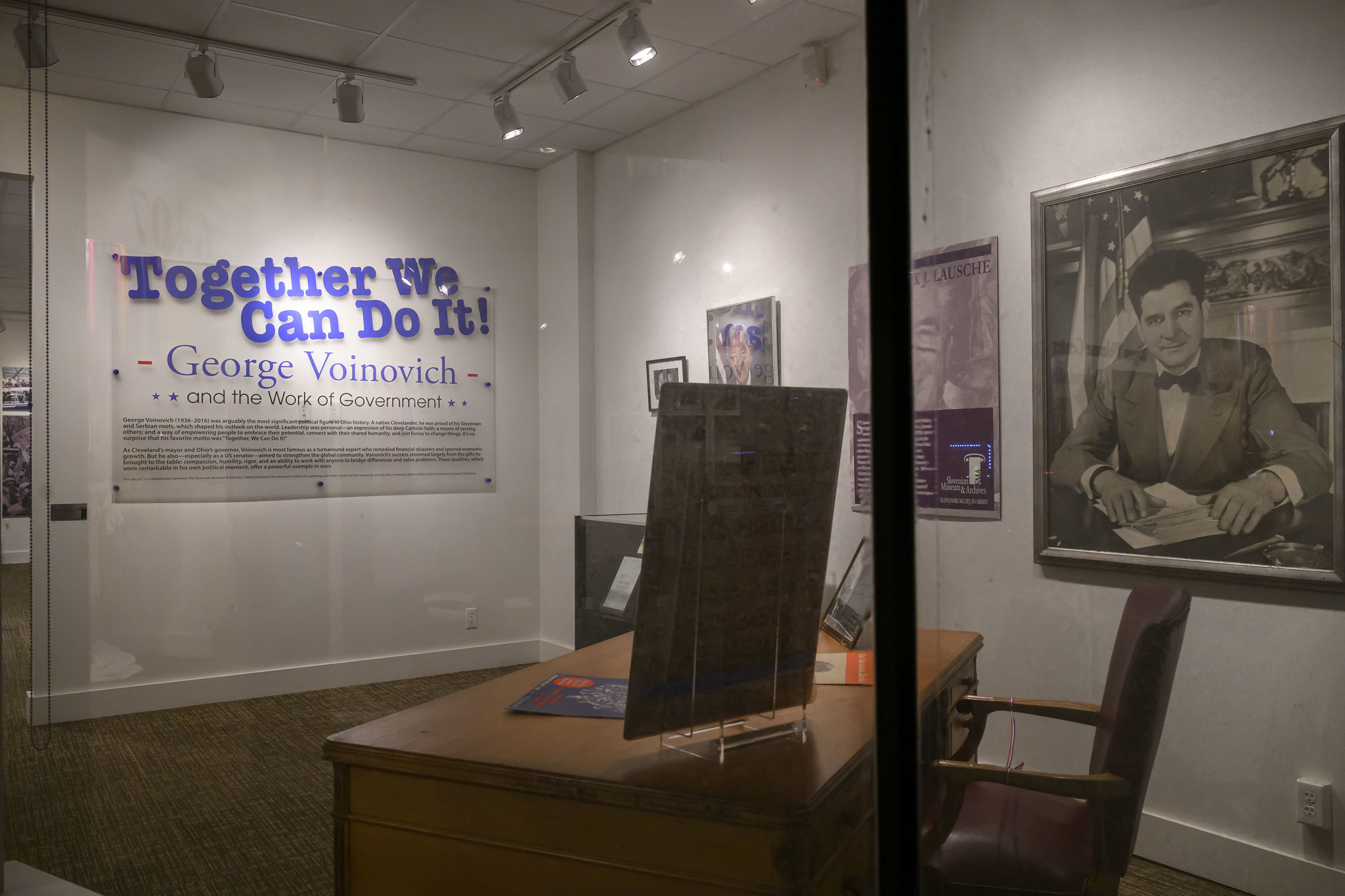 The "Together We Can Do it! George Voinovich" exhibit, which includes a desk, chair, several posters and a large photo of George Voinovich.