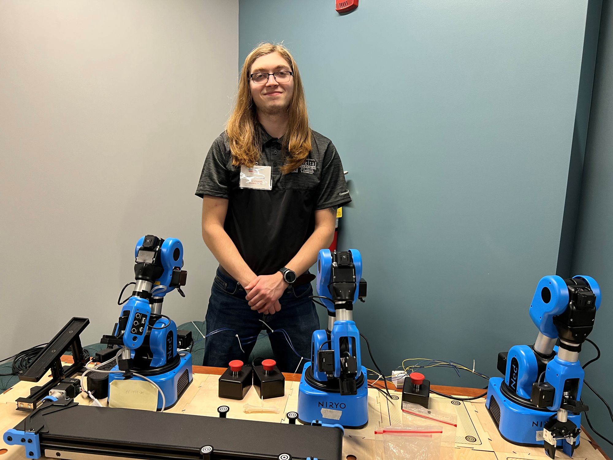 Petrie standing with robots during outreach. 