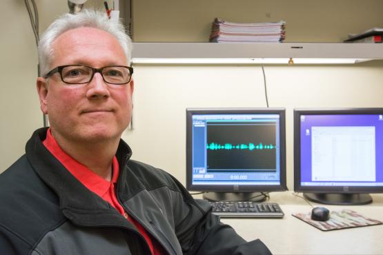 Jim Montgomery sits at a desk that has two computer screens on it.